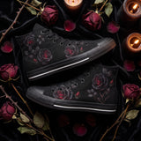 Thornveil Rose High Tops — gothic black roses with crimson centers and thorned stems on black — flat lay with candle and dried roses
